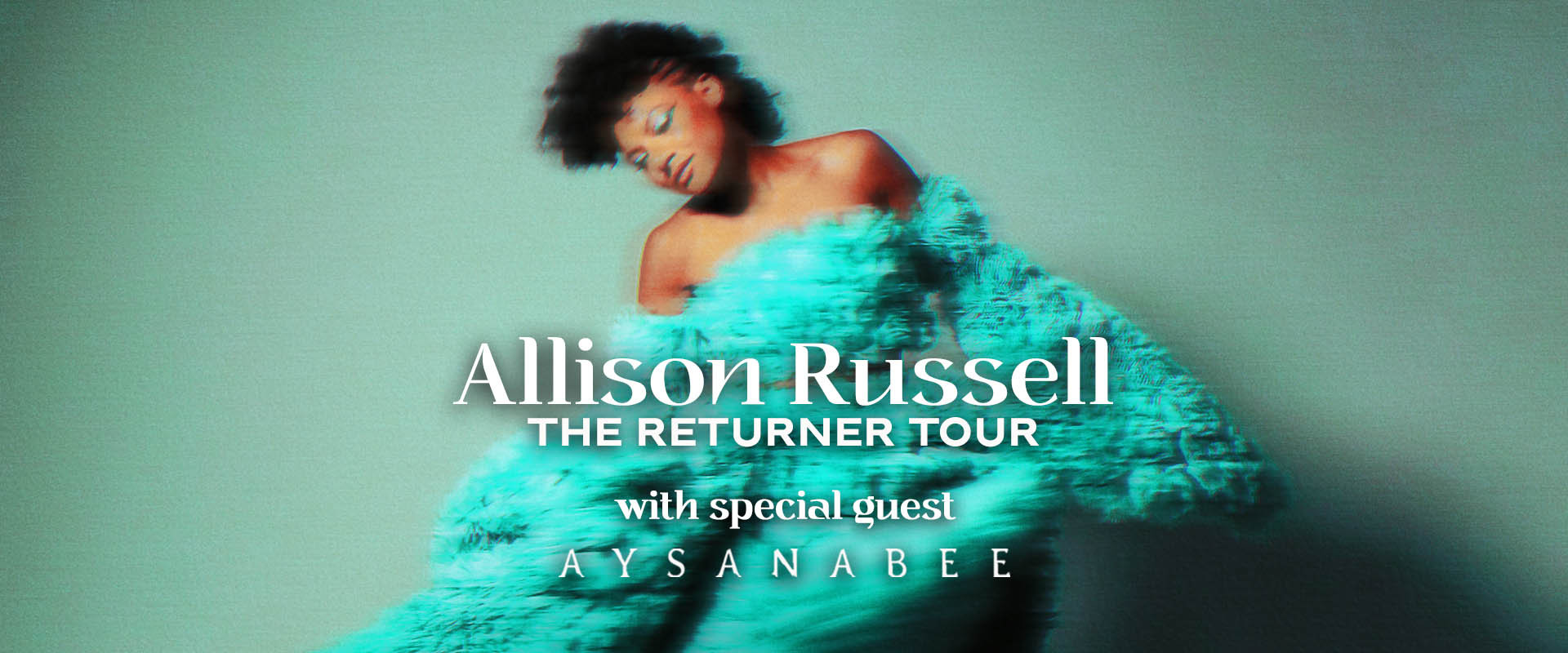 Allison Russell is wearing a strapless teal tulle dress and is standing in front of a teal background. The photo is artistically blurred. 