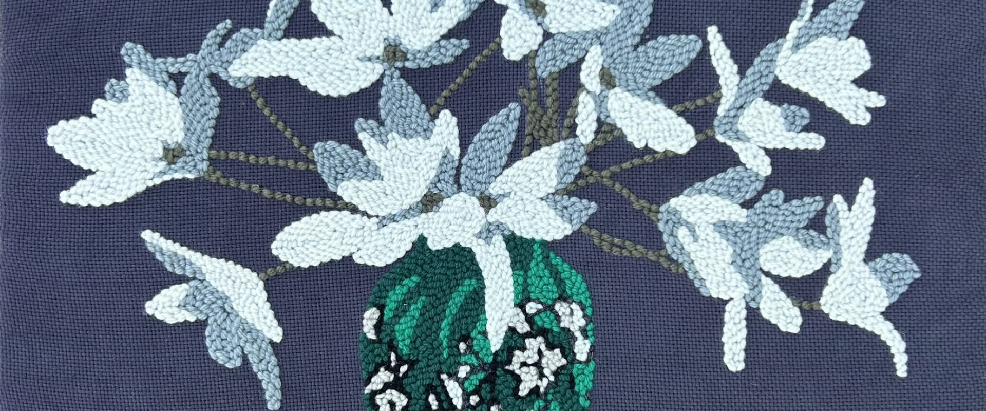 white flowers in a green and white vase on a dark grey background