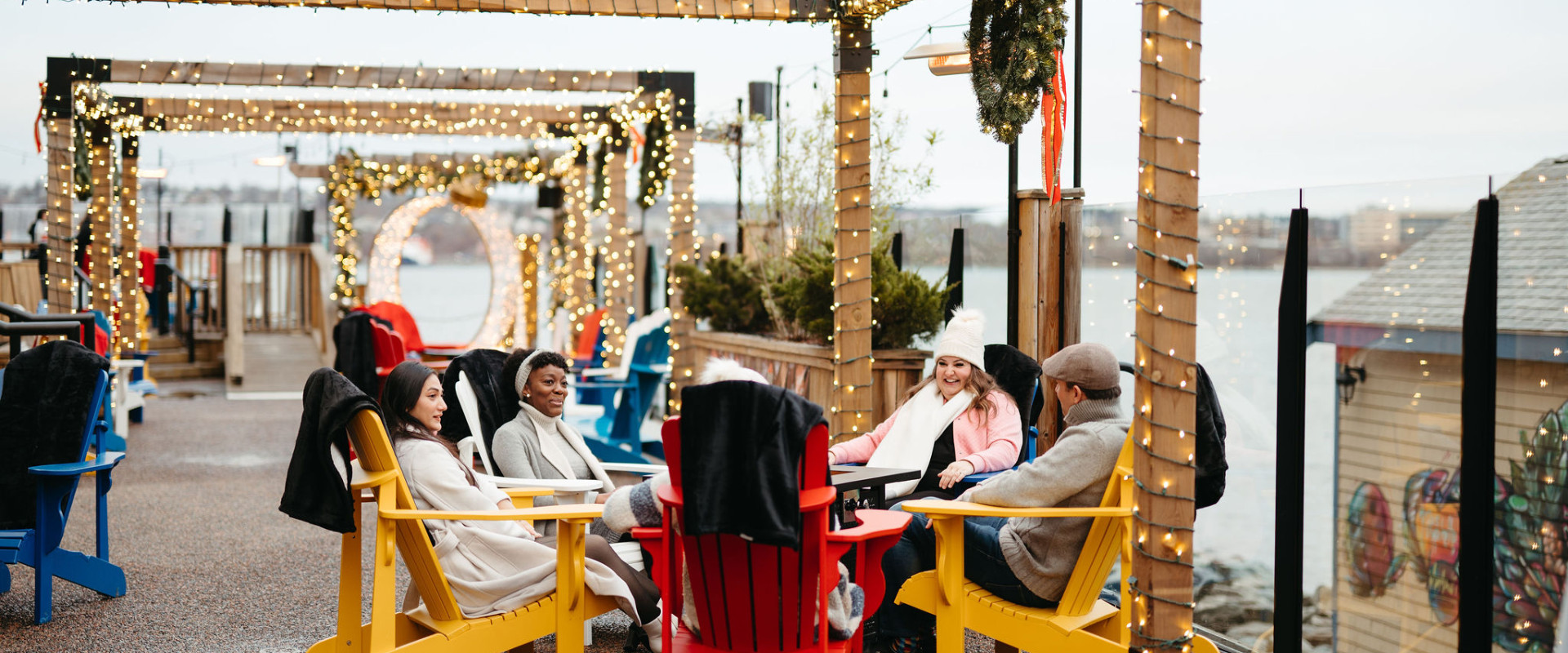 Friends gather round the fire on the Merry & Bright Patio at the Halifax Marriott Harbourfront