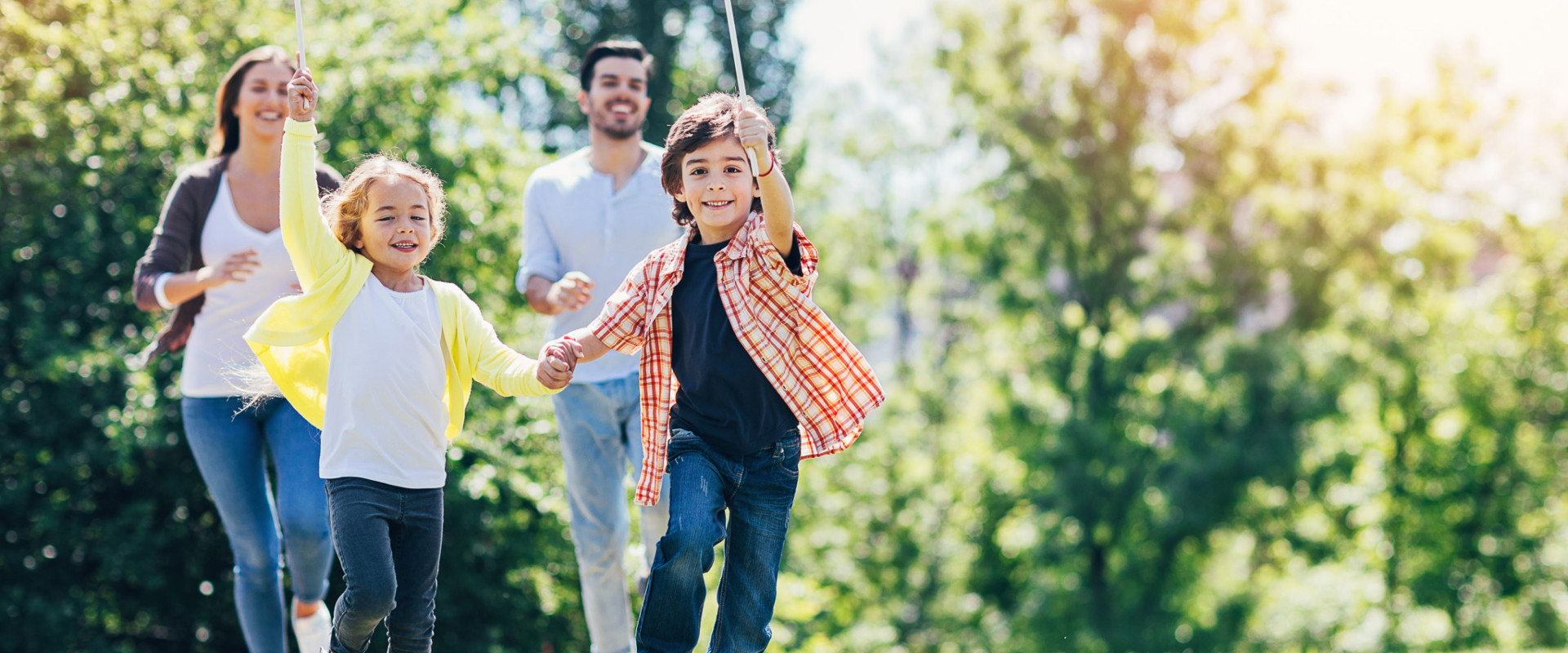 Family of four running and playing on the grass on a sunny day