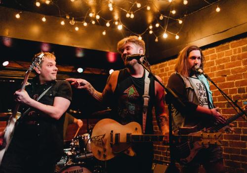 Three musicians with guitars performing on stage 