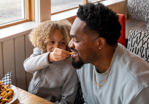 Father being fed French fries by his child