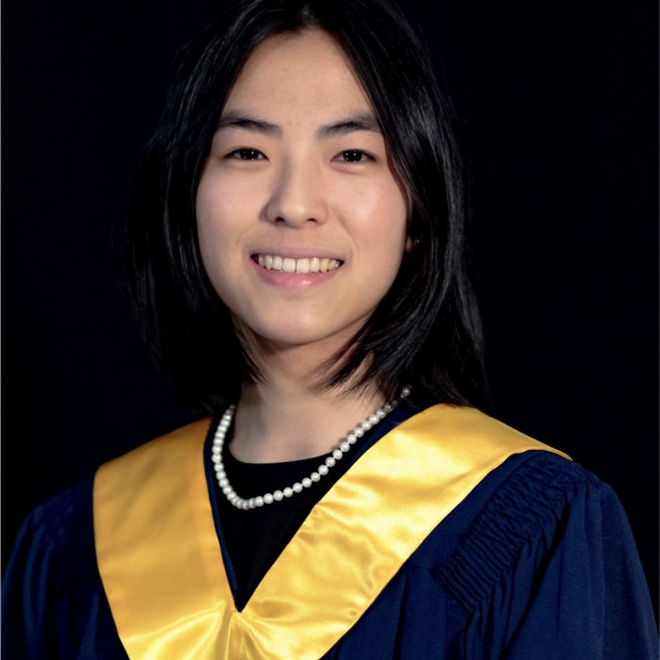 girl smiling wearing navy graduation gown with gold collar
